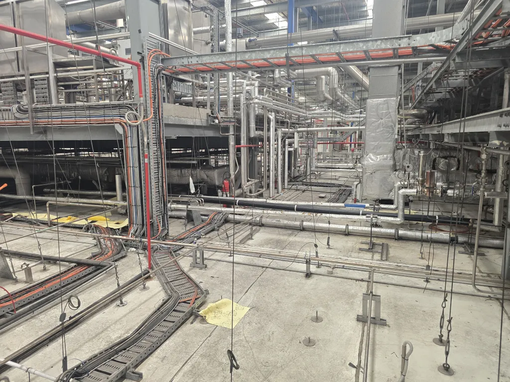Interior of an industrial plant with overhead services, pipework and steel framing