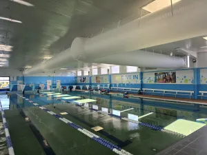 Indoor 25 m pool hall with a white fabric supply-air duct running the length of the ceiling