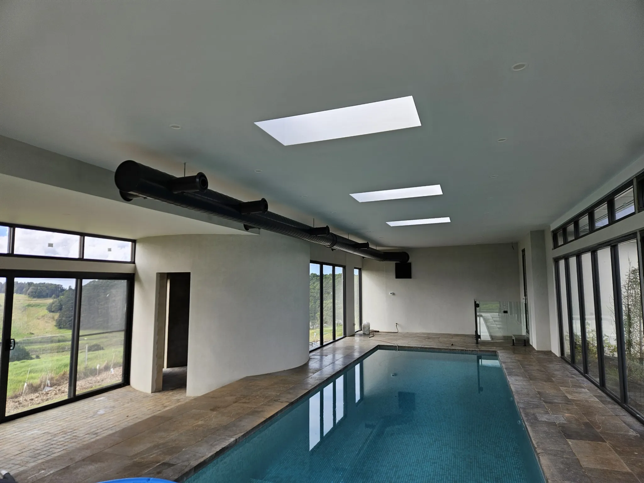 Indoor lap pool with a black spiral supply duct and skylights