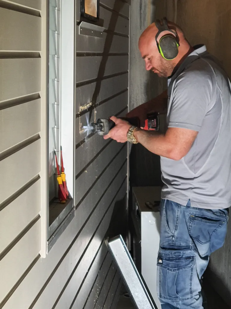 Technician servicing an air handling unit with a power tool