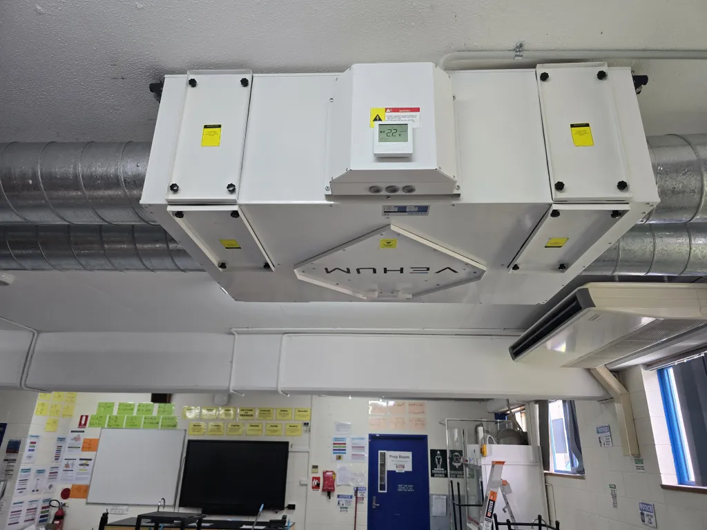 Close-up of a ceiling-suspended heat recovery ventilation unit in a classroom