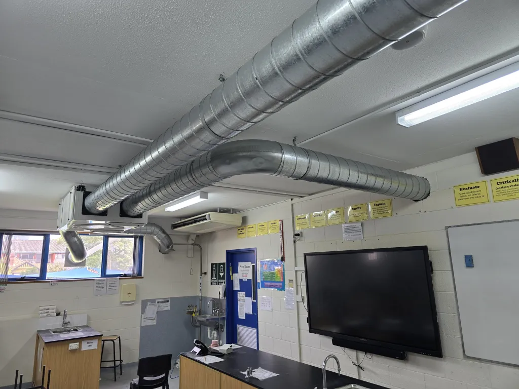 Branching spiral ductwork above a science classroom with an interactive screen
