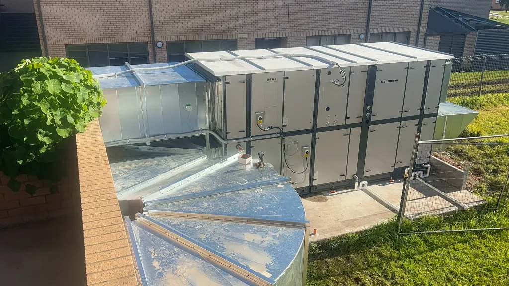 Packaged dehumidification and ventilation units installed outside a school pool building
